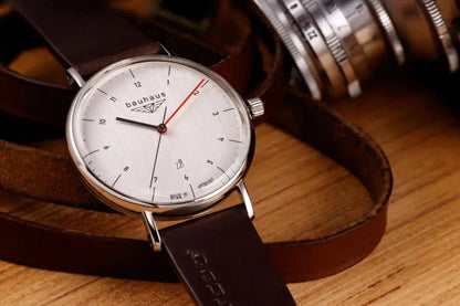 Bendixen-Braun Bauhaus men's watch with silver dial, date window, red minute hand, and brown leather strap.